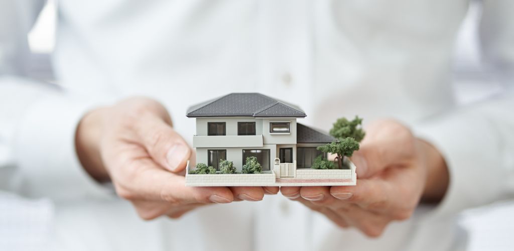 person holding a model house