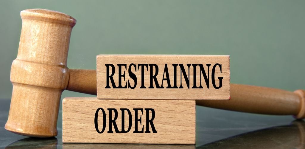 wooden gavel and blocks that say restraining order