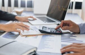 people working on a laptop and calculator with paper on a table or desk
