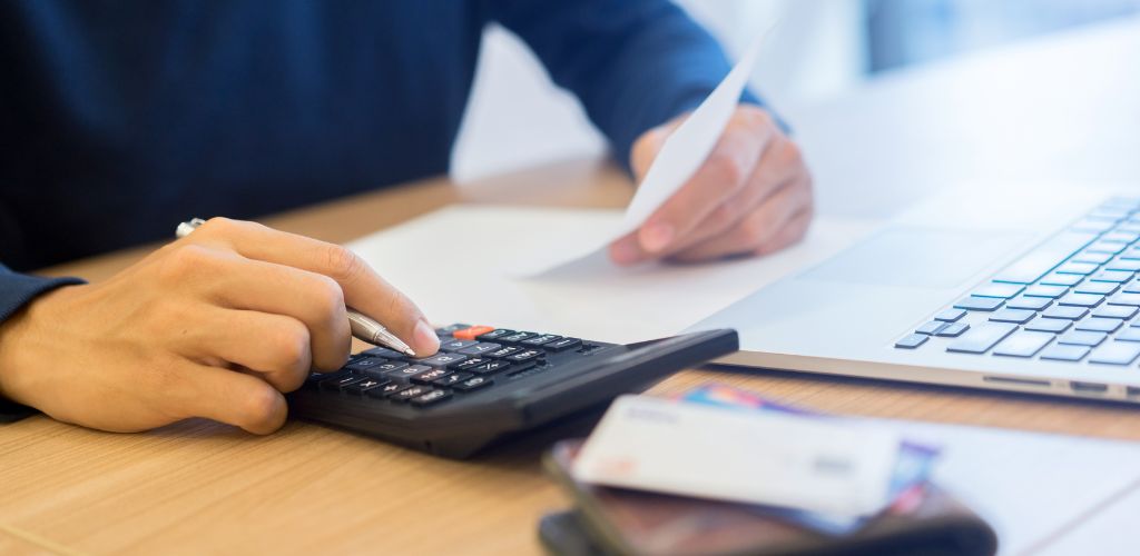 man at desk calculating and organizing paper