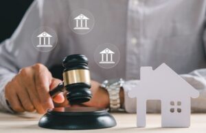 gavel with paper house miniature and floating columns illustrating legal activity with buildings