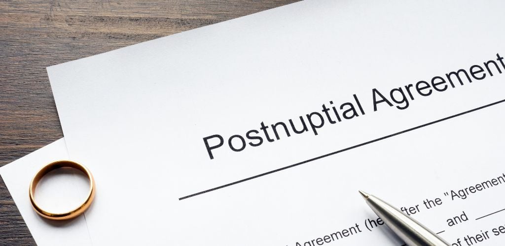 postnuptial agreement written on top of contract with a wedding ring and a pen sitting on it