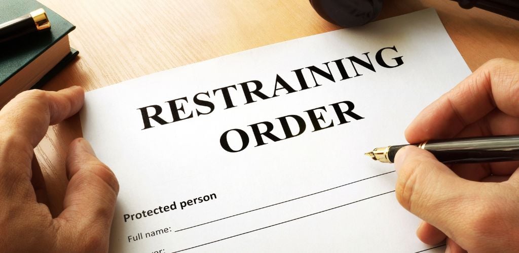 hands writing on a restraining order form